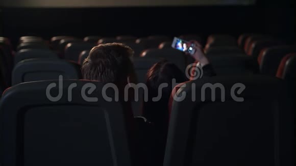 年轻人在空荡荡的电影院大厅接吻情侣拍自拍照片视频的预览图