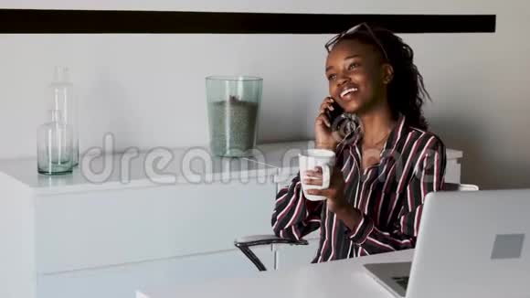 商务女青年在办公室边喝咖啡边用手机说话视频的预览图