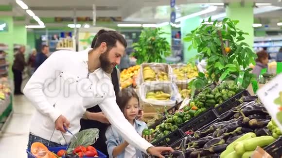 快乐的父母带着孩子选择新鲜的蔬菜把它们放在篮子里视频的预览图
