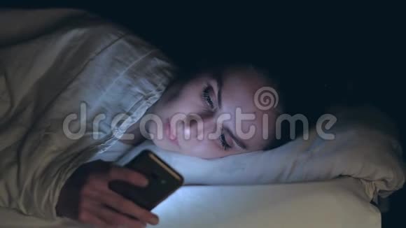 女人使用手机晚上躺在床上视频的预览图