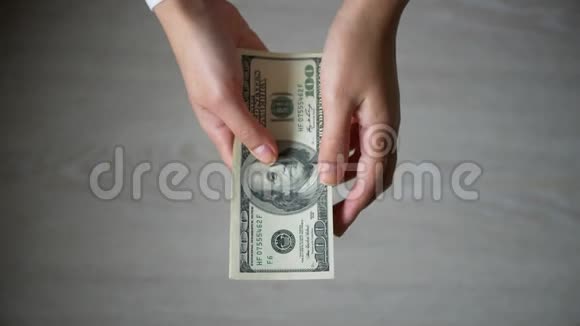 在灰色背景下男人的手数着100美元的钞票视频的预览图
