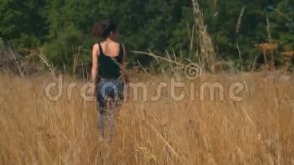 在阳光明媚的日子里年轻女子悲伤地沿着金色的田野走着视频的预览图