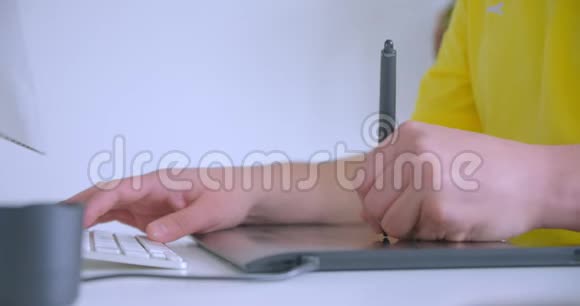 设计师手在办公室室内工作的平面触摸板上打字的特写镜头视频的预览图