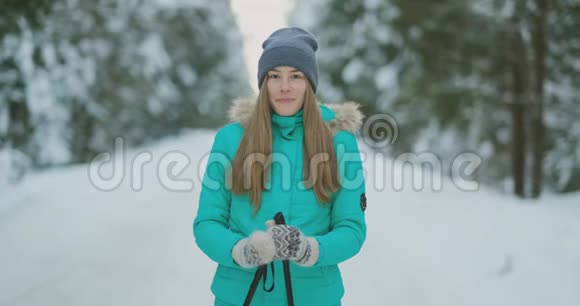 在大雪纷飞的冬天美丽的年轻女子一边欣赏滑雪一边开心地笑着看着摄像机视频的预览图