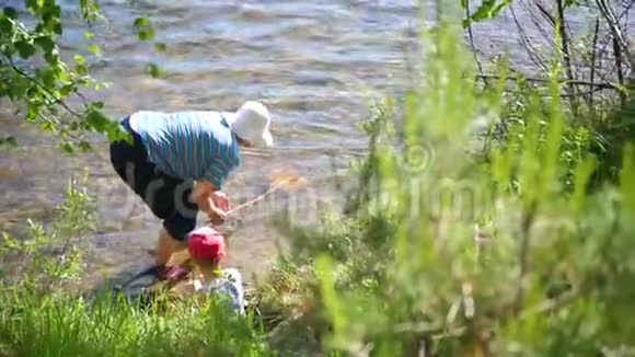 祖母和孙子钓鱼网山区河流的海岸夏日炎炎的清凉水视频的预览图