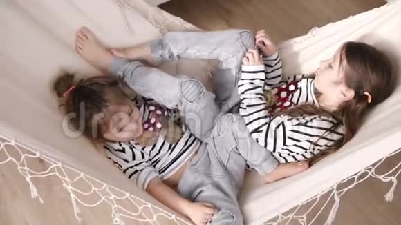 两个可爱的女孩在白色吊床上摇摆休息一下慢动作视频的预览图