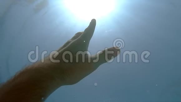 雄性的手从水下伸展到太阳光手臂寻求帮助并试图伸手到太阳观点视频的预览图