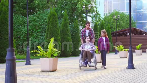 一家人在散步一个坐轮椅的残疾妇女视频的预览图