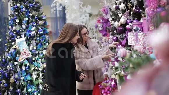 两个女人为圣诞商店的圣诞装饰品选择风景视频的预览图