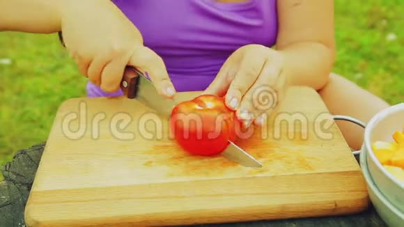那个女人她的手把熟透的西红柿切成木板上的薄片视频的预览图