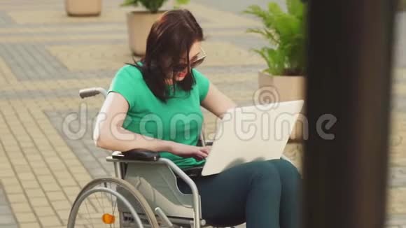 一个年轻漂亮的女商人坐在轮椅上用笔记本电脑打字慢悠悠视频的预览图