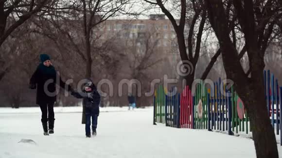 HD母亲和儿子一起在冬季公园里奔跑手牵手视频的预览图