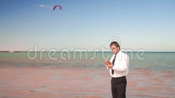 年轻的商人在海边用手机聊天视频的预览图