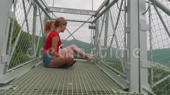 两个白种人金发碧眼的人坐在高山上的高桥上交流视频的预览图