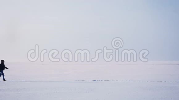 在雪地上向右行走的轮廓中的男性轮廓的宽镜头视频的预览图