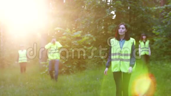 穿着绿色背心的志愿者的工作在日落时分在树林里寻找失踪的人视频的预览图
