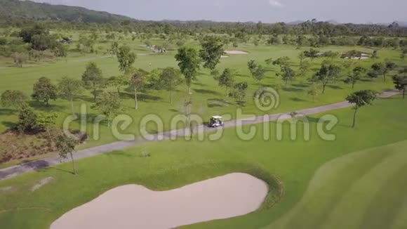 绿色高尔夫球场的顶部景观完美的热带场所道路上的高尔夫球车视频的预览图