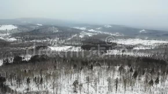 鸟瞰白雪皑皑的森林和山丘多云坏阴多雾天气无人驾驶飞机飞行视频的预览图