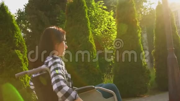 日落时分穿着轮椅衬衫的残疾女孩骑在公园里慢节奏视频的预览图