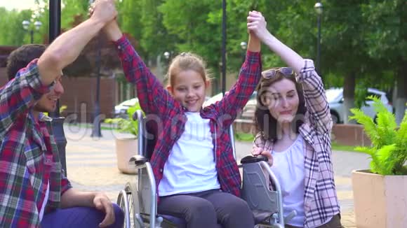 爸爸妈妈带着一个残疾的小女儿坐轮椅的肖像给五个慢动作视频的预览图