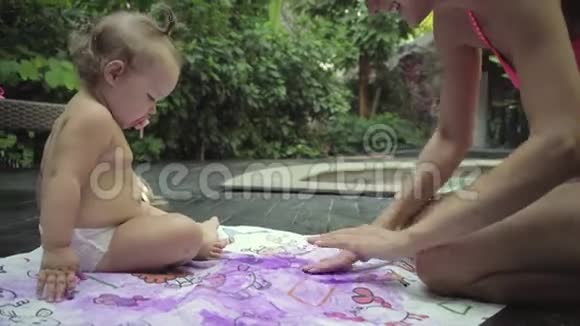 母亲带着孩子在花园的水池边画手指画儿童发展概念4k视频的预览图