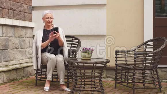美丽的女人正在街头咖啡馆喝咖啡发信息视频的预览图