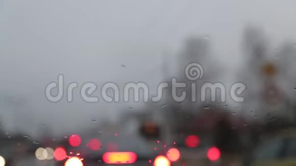 从一辆汽车的内部可以看到下雨的阴郁天气雨刷积极地清除挡风玻璃上的雨滴视频的预览图