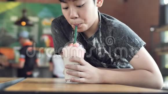小男孩在咖啡馆里微笑着喝奶昔视频的预览图