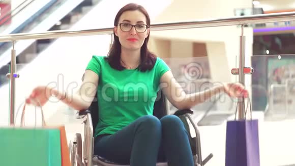 坐在轮椅上的残疾妇女展示购物包并对相机微笑关门视频的预览图
