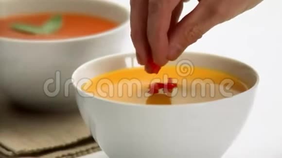 厨师在一碗红汤旁边端着奶油南瓜汤视频的预览图