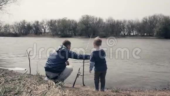 年轻的父亲和小儿子一起在河边钓鱼视频的预览图