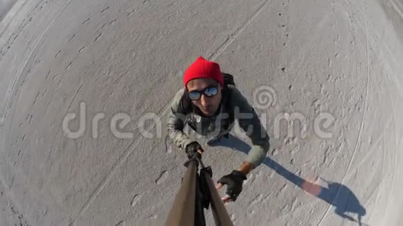 一位戴着红帽子带自拍棒的旅行者在干盐湖上拍照视频的预览图