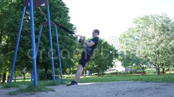 在多风的夏季公园里人们在健身圈上做剧烈的拉力运动4K慢动作镜头视频的预览图