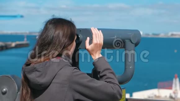 不可辨认的黑发女人透过望远镜看海视频的预览图
