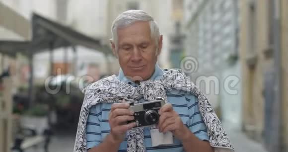 高级男性游客探索小镇用复古相机拍照视频的预览图