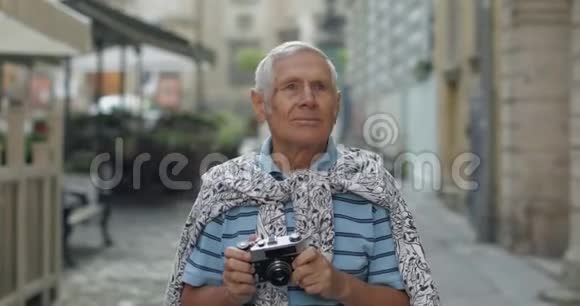 高级男性游客探索小镇用复古相机拍照视频的预览图