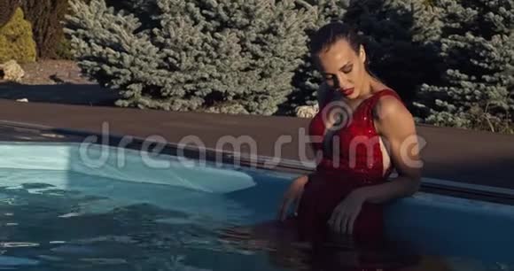 穿着红色衣服的湿女人站在游泳池里摆姿势4K视频的预览图