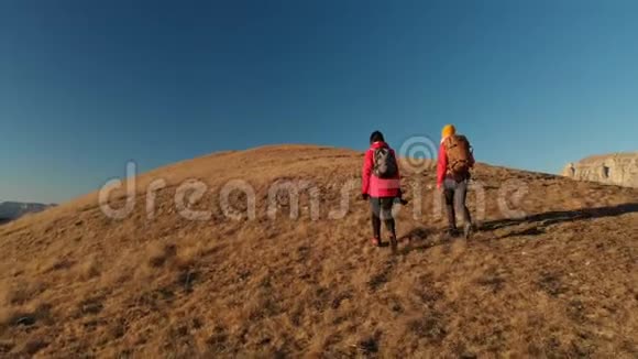 两位带着背包和照相机的女游客在山上史诗般的岩石之间的山景视频的预览图