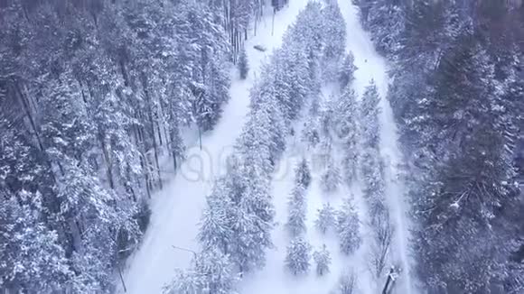 冬季森林积雪道路上的汽车俯视图剪辑汽车在大雪纷飞的道路上开到路边视频的预览图