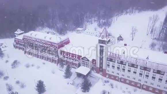 降雪时在森林里度假剪辑红色综合度假村风格的城堡包围森林在雪多云视频的预览图