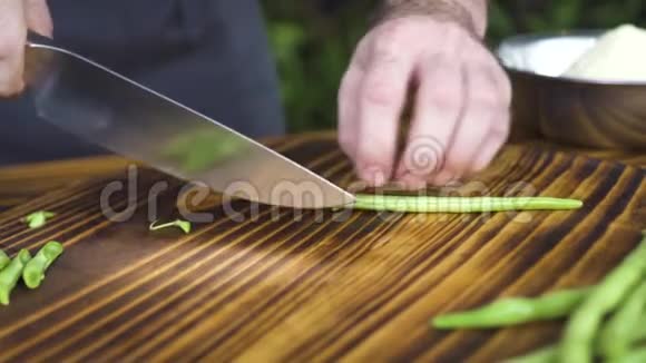 厨师用刀切青豆在木桌上慢动作合上雄性手切青豆蔬菜视频的预览图