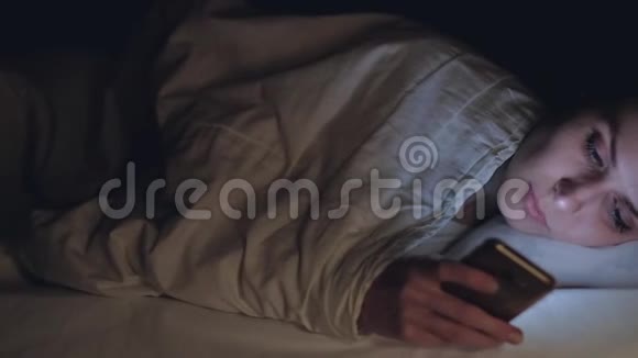 女人使用手机晚上躺在床上视频的预览图