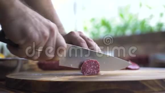 把刀关在男手上在木桌上切香肠沙拉米厨师切成薄片脂肪香肠视频的预览图