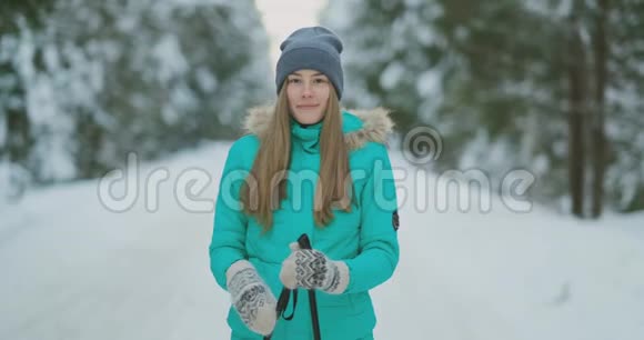 在大雪纷飞的冬天美丽的年轻女子一边欣赏滑雪一边开心地笑着看着摄像机视频的预览图