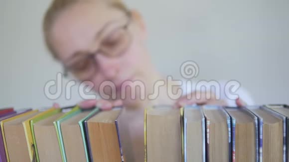 图书馆里戴眼镜的女人正在书架上的书中搜寻视频的预览图