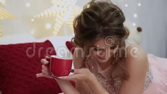非常漂亮的女孩在圣诞床上喝茶视频的预览图