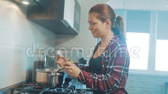 漂亮的女人在厨房里做饭和测试食物厨房里的女孩把磨碎的胡椒粉倒在汤里视频的预览图
