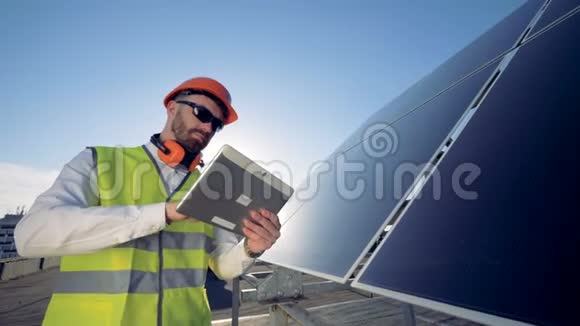 一名工人靠近太阳能电池板关门他的平板电脑就在太阳能电池旁边视频的预览图