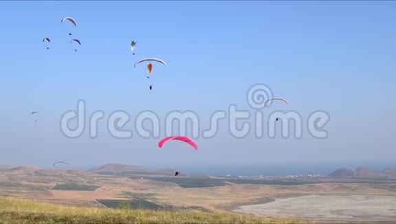 有许多飞行滑翔伞在田野和海洋上的景观视频的预览图