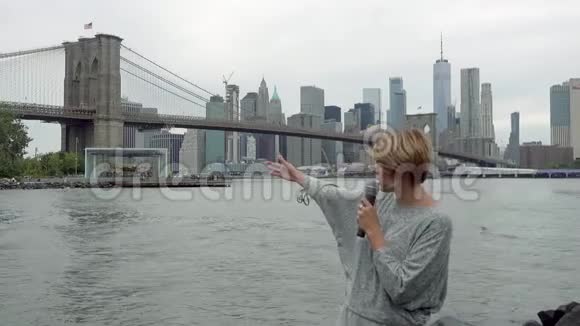 年轻的女电视记者在曼哈顿摩天大楼的背景下播出视频的预览图